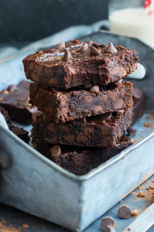 Stacked homemade chocolate chip brownies with a bite on the first piece.