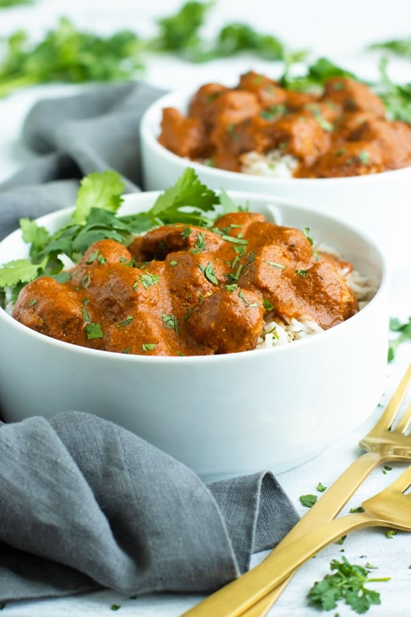 Two white bowls filled with Slow Cooker Chicken Tikka Masala and rice.