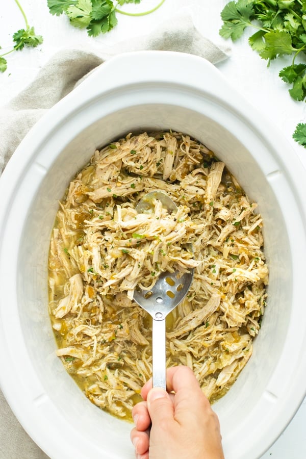 Easy crockpot shredded chicken in a slow cooker bowl with a spoon inside.