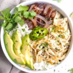 Slow Cooker Shredded Chicken in a white bowl with rice and sliced avocados.