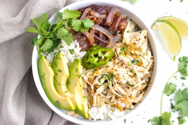 Slow Cooker Shredded Chicken in a white bowl with rice and sliced avocados.