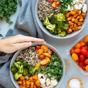 Two hands holding a gray bowl filled with a veggie quinoa bowl recipe.