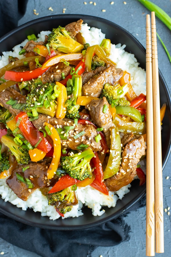 Gluten-free beef and broccoli stir fry with rice and chopsticks.