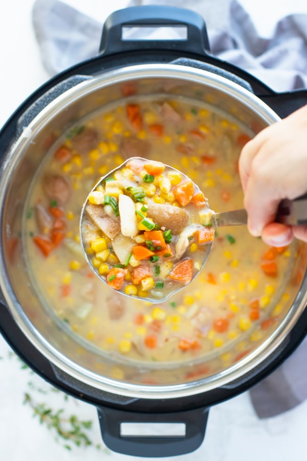 A ladle of gluten-free potato corn chowder above an Instant Pot.