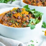 Chicken Chili recipe in a white bowl with cilantro as a garnish.