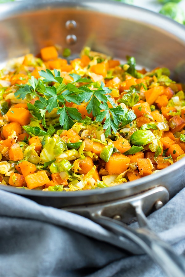 Picture of a silver skillet containing Brussel sprouts and sweet potatoes for an easy weeknight dinner.
