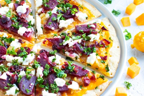 Butternut squash pasta sauce on a gluten-free pizza crust with beets, goat cheese, and kale.