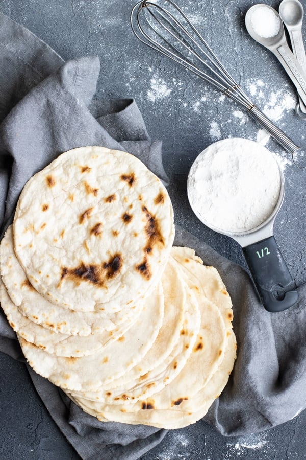 Paleo tortillas on a gray napkin with a half-cup of cassava flour next to them.