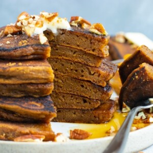 Stack of healthy pumpkin pancakes with a bite taken out.