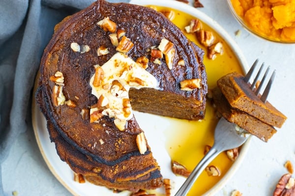 Pumpkin pancakes recipe on a white plate with a fork.