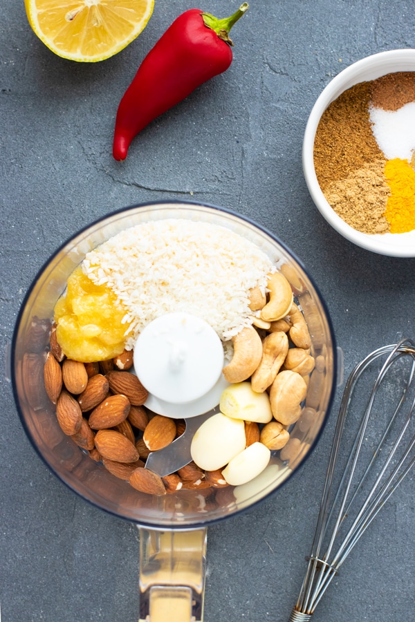 Cashews, almonds, garlic cloves, Indian seasonings, and ginger paste in a food processor bowl to make a korma sauce recipe.