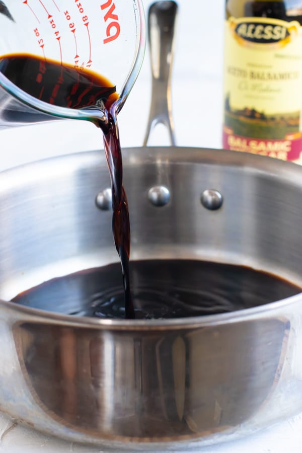 Balsamic vinegar of Modena being poured into a stainless steel saucepan for a sauce.