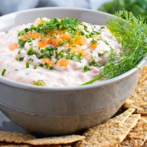 A grey bowl full of salmon dip that is topped with smoked salmon and dill.