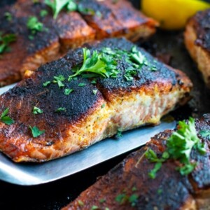 Blackened salmon being picked up by a metal spatula from a skillet.