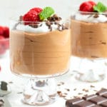 Two parfait glasses full of an easy chocolate mousse recipe with whipped cream, raspberries and mint leaves on top.