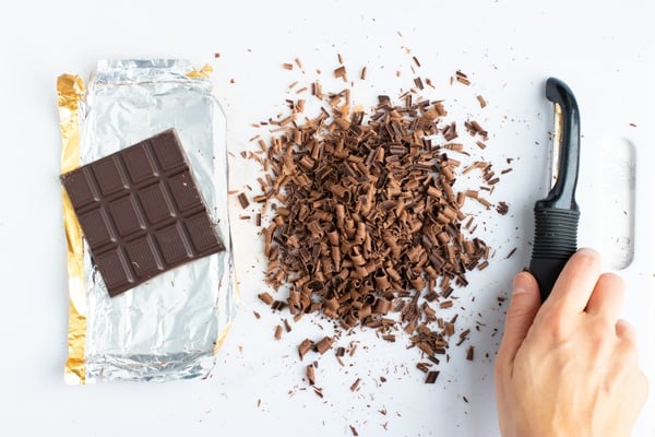 Showing how to make chocolate curls from a chocolate bar with a potato peeler.