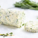 A log of garlic herb butter on a white background.