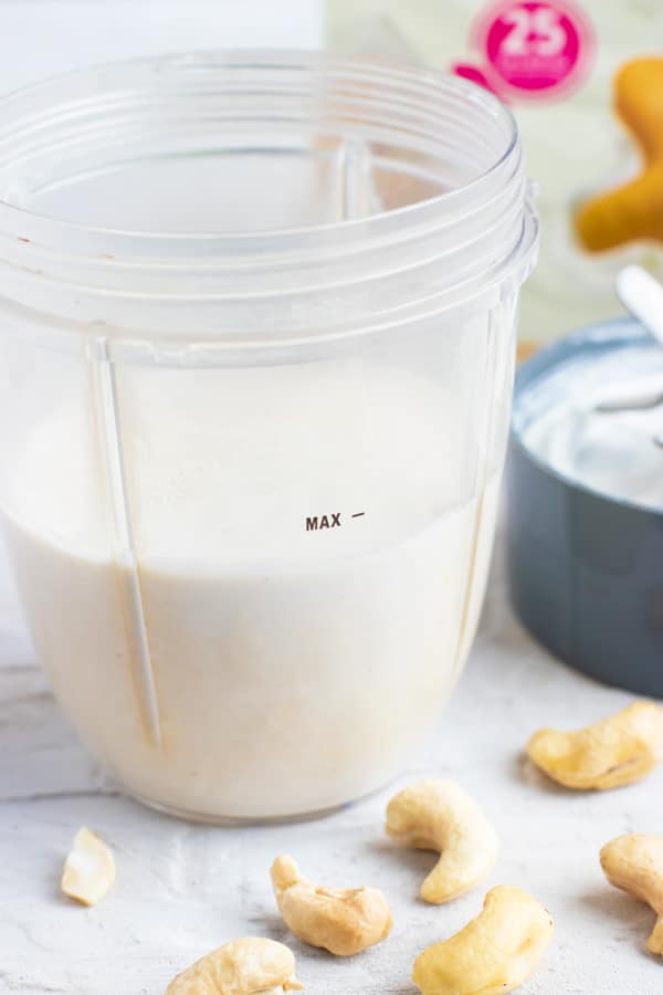 Cashew cream in a blender cup to be used as a replacement for heavy cream in a soup recipe.