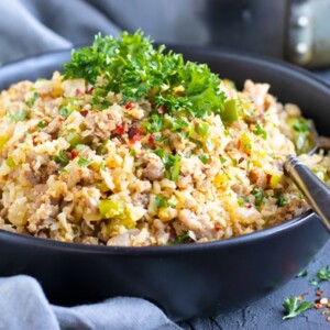 A large serving bowl with a spoon full of cauliflower dirty rice recipe.
