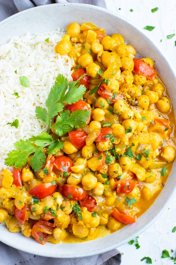 A large white bowl full of a vegetarian Indian curry made with chickpeas and tomatoes.