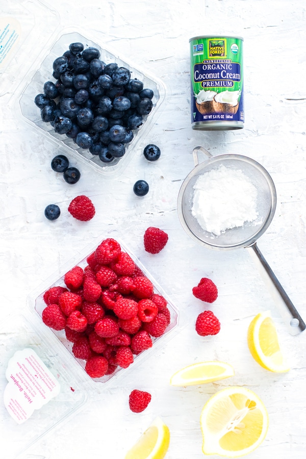 Blueberries, raspberries, coconut cream, powdered sugar, and fresh lemons and topping ideas for pancakes.