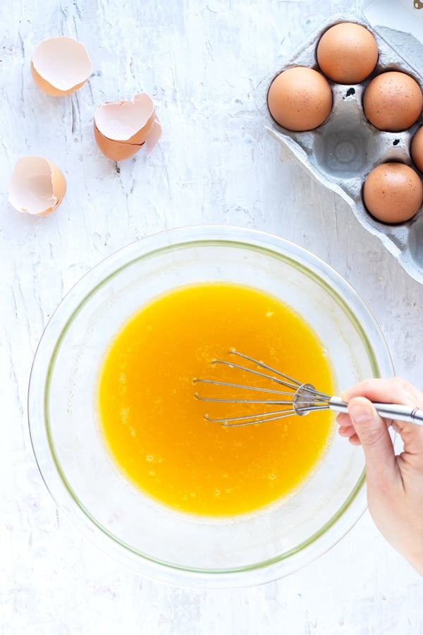 Eggs, coconut oil, and honey being whisked together to show how to make lemon poppy seed muffins.