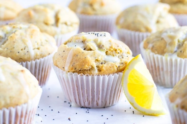 Lemon Poppy Seed Muffins with a lemon glaze on a white table.