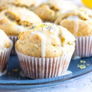 A tray full of healthy, gluten-free lemon muffins with a powdered sugar glaze and poppy seeds.