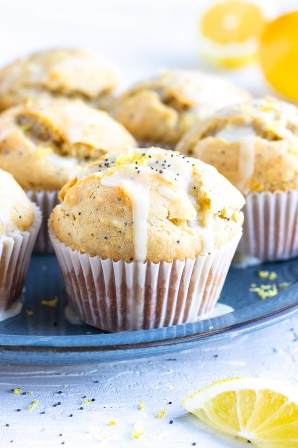 A tray full of healthy, gluten-free lemon muffins with a powdered sugar glaze and poppy seeds.