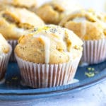 A blue plate full of healthy breakfast lemon muffins with powdered sugar glaze and poppy seeds on top.