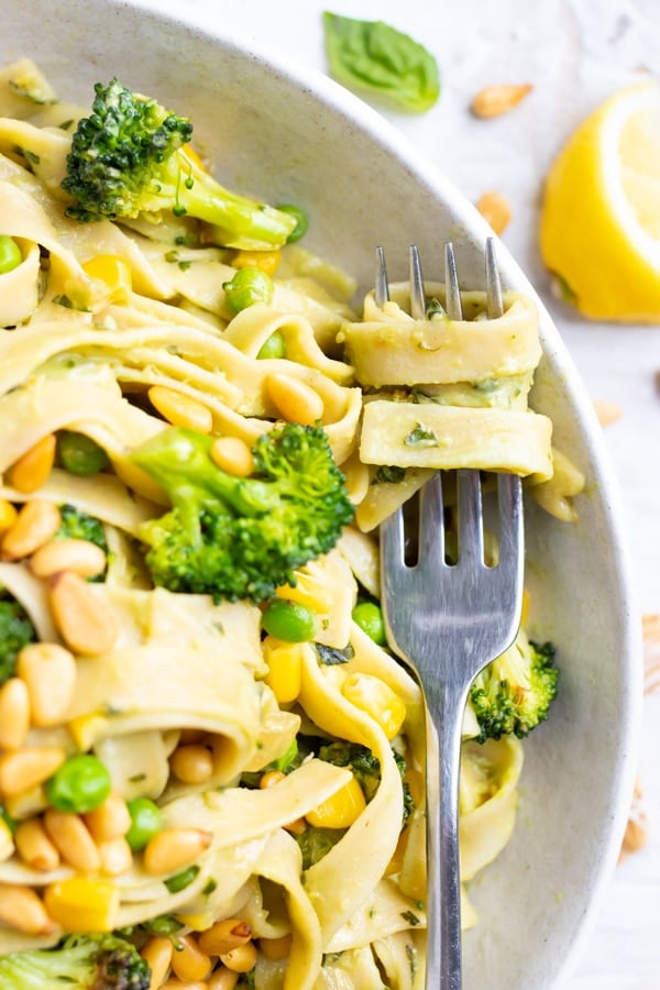 A fork with vegan pasta wrapped around it that has been tossed in an avocado pasta sauce.