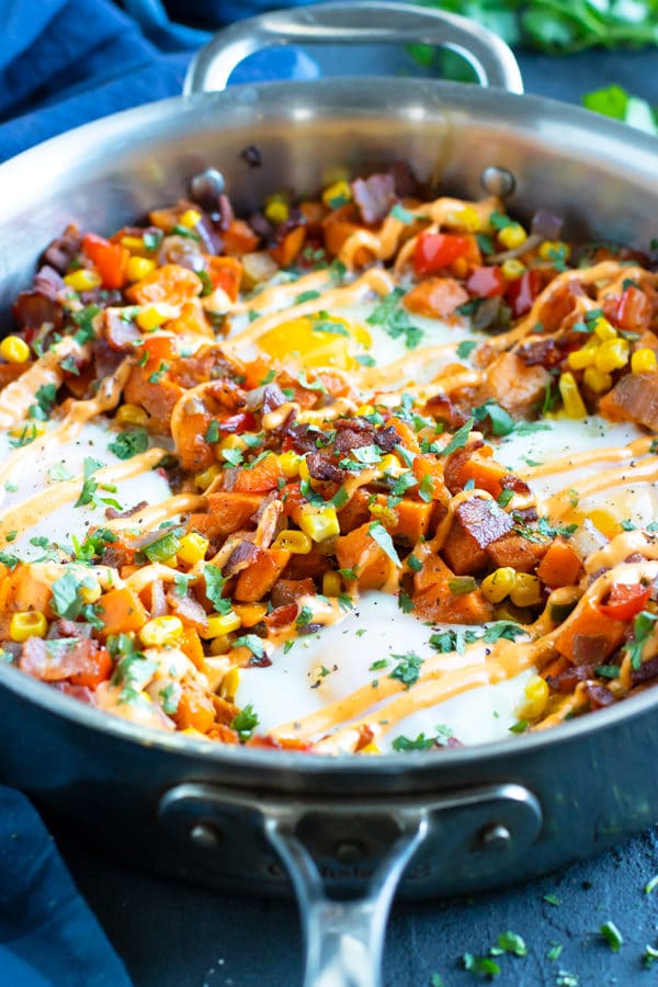 A skillet full of a sweet potato hash recipe with eggs.