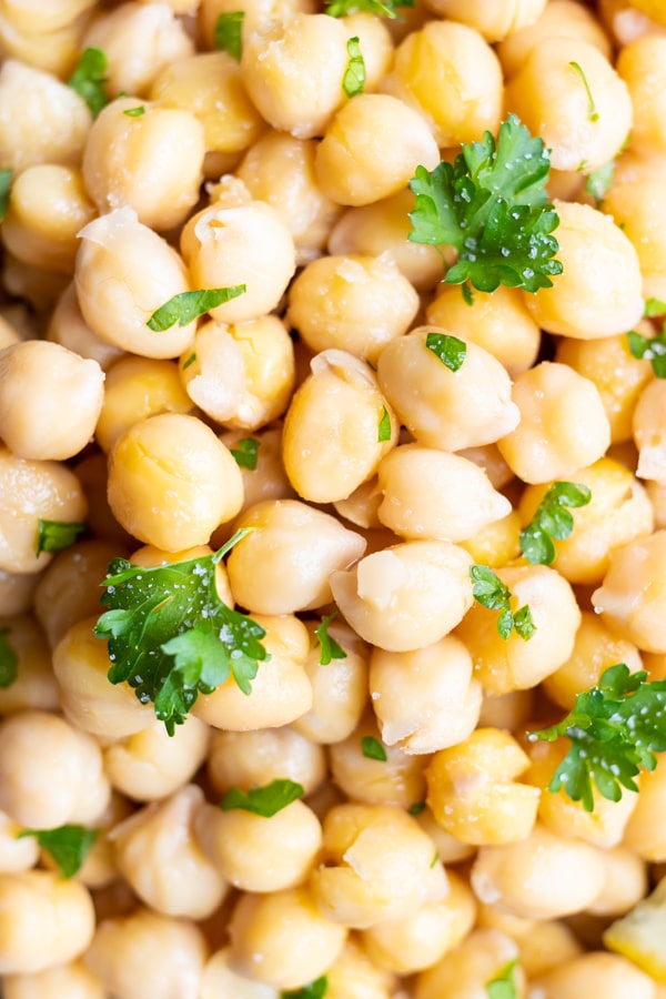 A close-up image of cooked garbanzo beans with parsley that shows how to cook chickpeas from scratch.