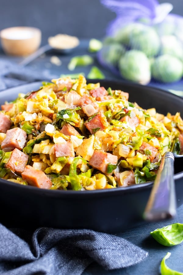 A serving bowl full of the best Brussels sprouts recipe that have been sautÃ©ed in a skillet with leftover ham.