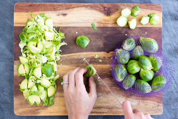 A person demonstrating how to shred Brussels sprouts by cutting them with a knife.