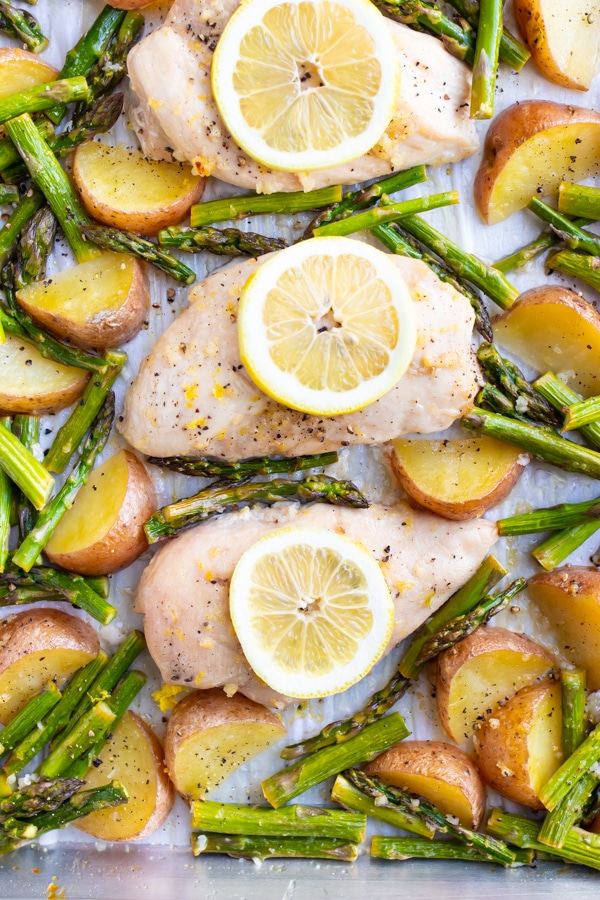 Healthy lemon garlic chicken recipe with asparagus and red potatoes that has been baked in the oven.