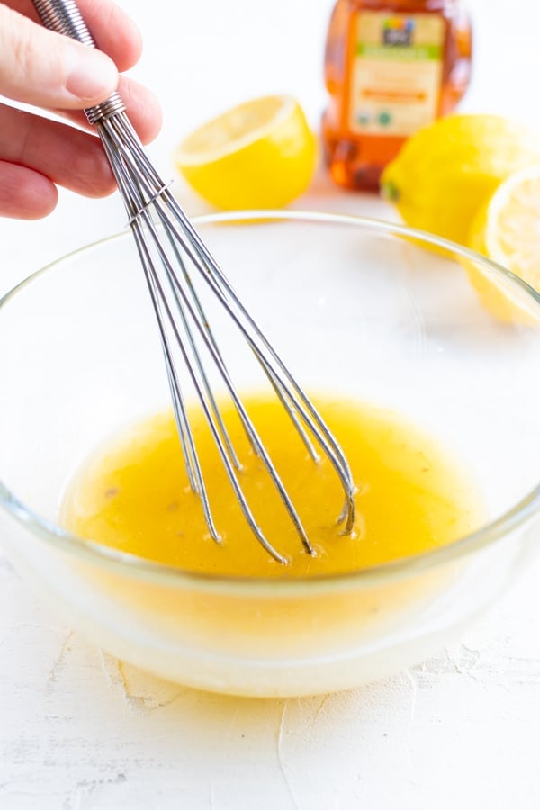 A lemon garlic butter sauce being whisked in a clear bowl for an oven baked chicken breast recipe.