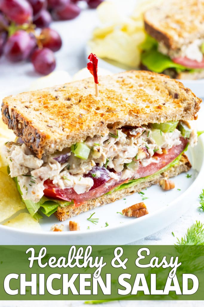 Chicken salad sandwich with a red toothpick on a white plate with potato chips.