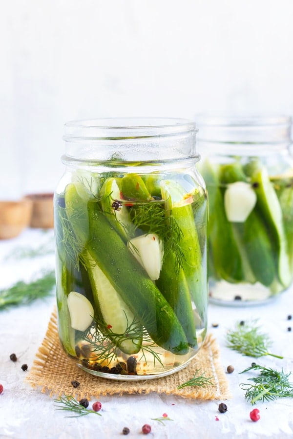 Pickled cucumbers in a glass jar with pickle juice that is made from vinegar, sugar, and salt.