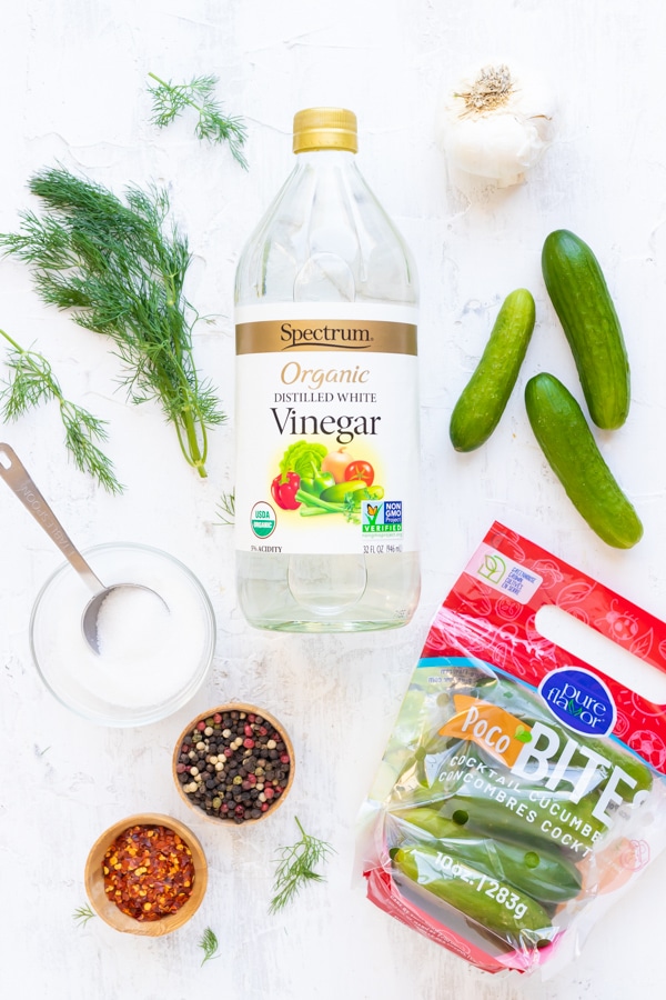 Distilled white vinegar, cucumbers, sugar, dill, garlic, peppercorns, and salt as the ingredients needed for an easy refrigerator pickles recipe.