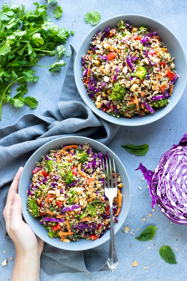 A hand holding a bowl full of a healthy quinoa salad.