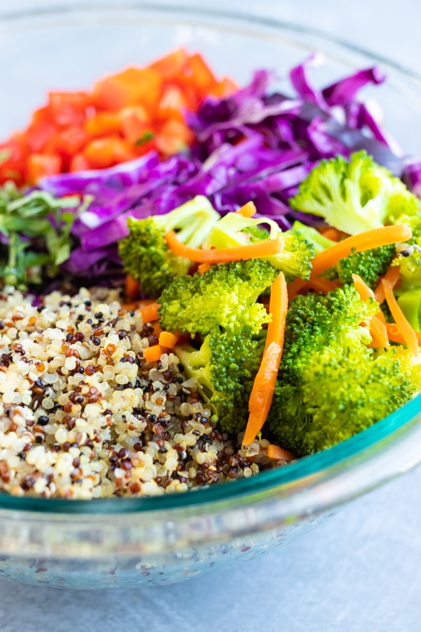Tri-color quinoa, broccoli, cabbage, and red bell peppers in a glass bowl.