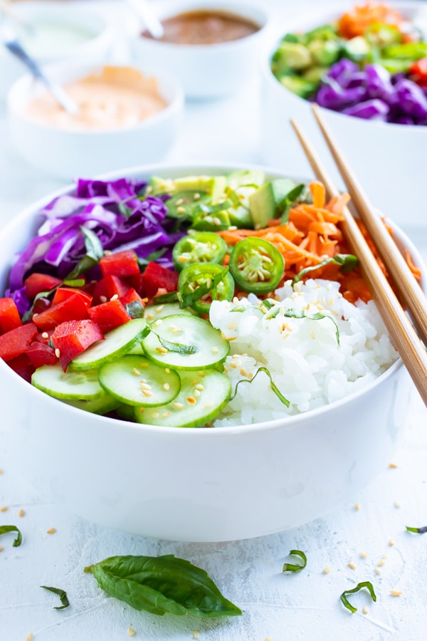 Vegan sushi bowls made with perfect sushi rice, cucumbers, bell peppers, avocado, carrots, and cabbage.