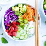 A large white bowl full of sushi rice, chopped vegetables, and sriracha mayo.