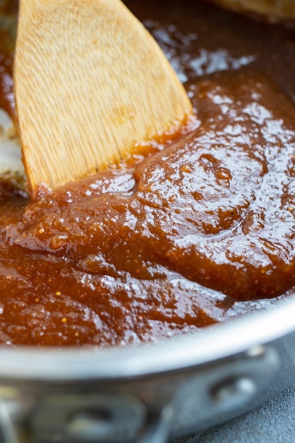 A wooden spoon demonstrating the right consistency of homemade fig jam.