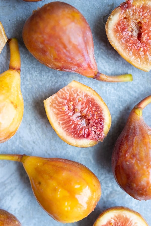 Whole brown turkey figs and a fig that has been cut in half.