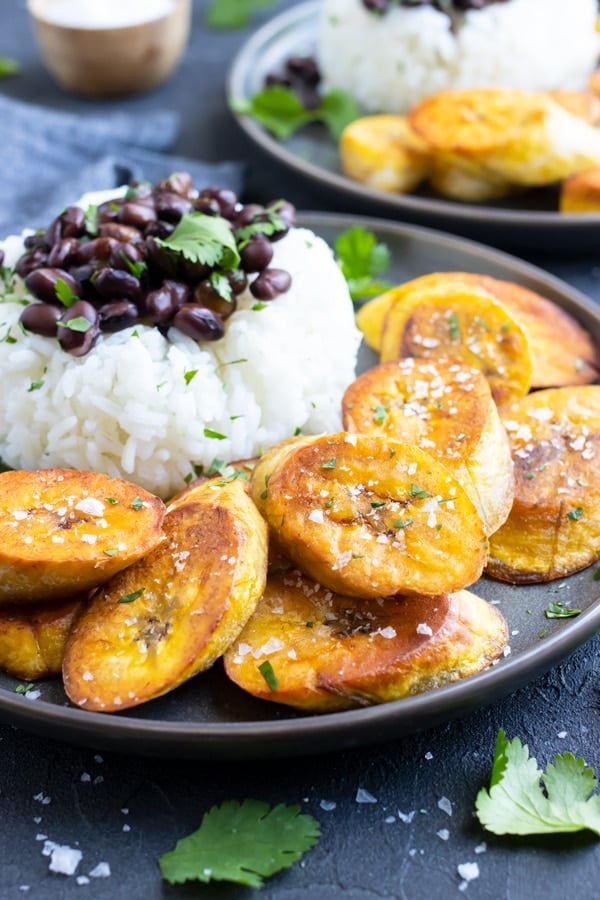 Fried plantains on a plate with rice and beans.
