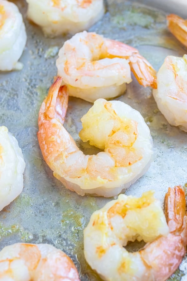 Pan-searing shrimp in a stainless steel skillet for a Pesto Shrimp Pasta recipe.