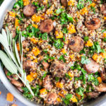 A large skillet with a healthy quinoa recipe full of kale, sweet potatoes, and sausage.