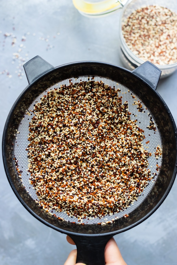 Rinsing and draining tri-color quinoa in a fine mesh strainer.